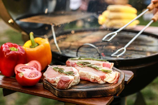 Planche avec viande crue et légumes près du barbecue en plein air — Photo