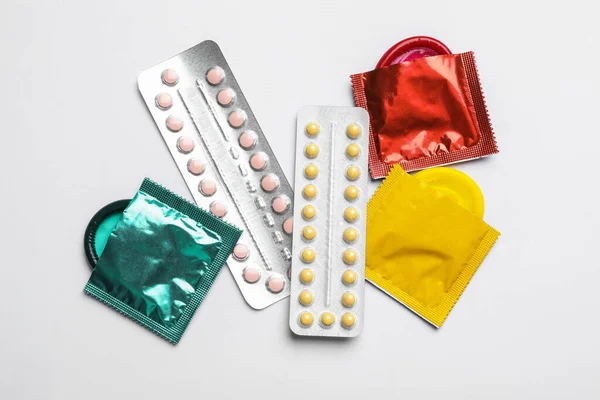 Презервативы и противозачаточные таблетки на белом фоне, вид сверху. Безопасный секс — стоковое фото