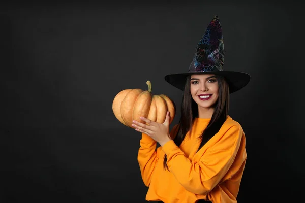 Όμορφη γυναίκα φορώντας κοστούμι μάγισσα με κολοκύθα για το Halloween κόμμα σε μαύρο φόντο, χώρος για κείμενο — Φωτογραφία Αρχείου