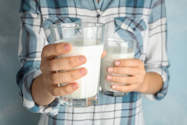 Kvinna innehav glasögon av hampa mjölk på ljusblå bakgrund, närbild — Stockfoto