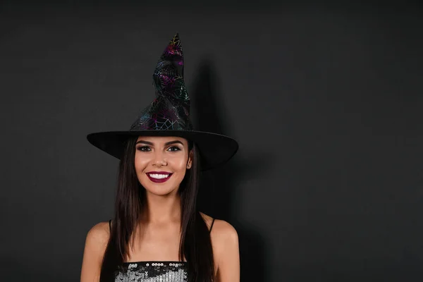 Hermosa mujer con traje de bruja para la fiesta de Halloween sobre fondo negro, espacio para el texto —  Fotos de Stock