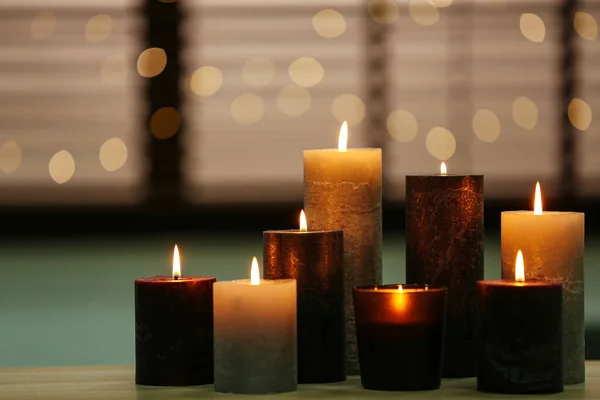 Mooie brandende kaarsen op houten tafel tegen feestelijke lichtjes. Ruimte voor tekst — Stockfoto