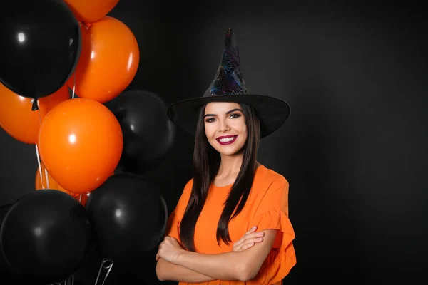 Hermosa mujer con traje de bruja con globos para la fiesta de Halloween sobre fondo negro —  Fotos de Stock