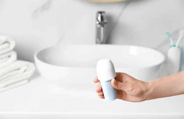 Mulher segurando desodorizante roll-on na casa de banho, vista de perto. Espaço para texto — Fotografia de Stock