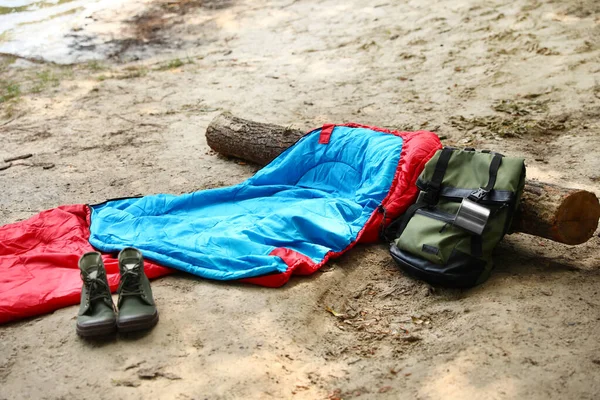 Sac de couchage, sac à dos avec tasse et bottes sur la plage — Photo