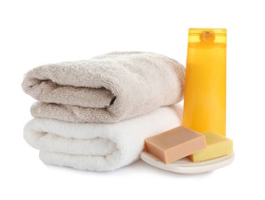 Beyaz arka planda katlanmış yumuşak havlular ve tuvalet malzemeleri