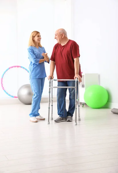 Caretaker helpen oudere man met Walking frame binnenshuis — Stockfoto