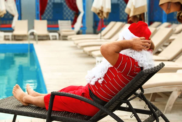 Authentique Père Noël sur chaise longue près de la piscine à la station — Photo