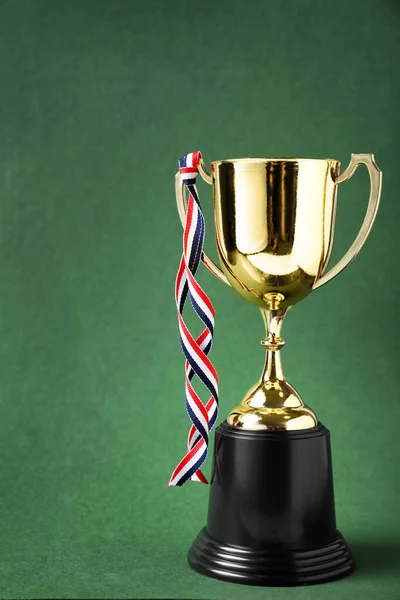 Copa trofeo dorado con cinta sobre fondo verde —  Fotos de Stock