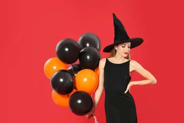 Bella donna che indossa costume da strega con palloncini per la festa di Halloween su sfondo rosso — Foto Stock