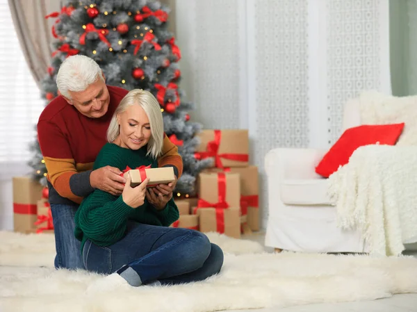 Šťastný dospělý pár s vánočním dárkem doma — Stock fotografie