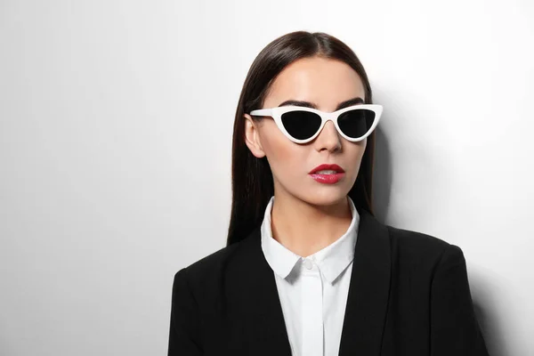 Joven mujer de negocios en gafas de sol con estilo sobre fondo claro — Foto de Stock