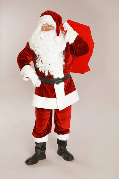 Authentische Weihnachtsmann mit Tasche voller Geschenke auf grauem Hintergrund — Stockfoto