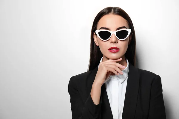 Joven empresaria con gafas de sol elegantes sobre fondo claro, espacio para texto — Foto de Stock