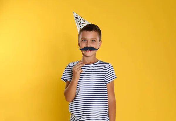 Sarı arka planda fotoğraf kabini aksesuarları olan küçük bir çocuk. Doğum günü kutlaması — Stok fotoğraf