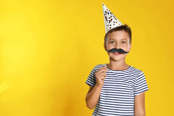 黄色の背景に写真ブース小道具を持つ小さな男の子、テキストのためのスペース。誕生日のお祝い — ストック写真