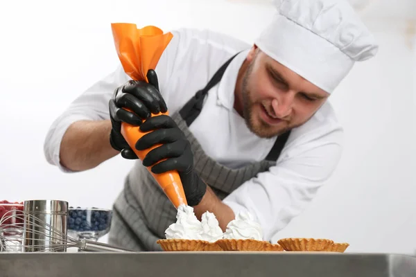 Pastelero preparando postres en la mesa en la cocina —  Fotos de Stock