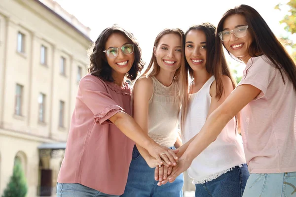 Mujeres felices poniendo las manos juntas al aire libre. concepto de poder chica — Foto de Stock