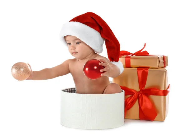 Симпатичный маленький ребенок в шляпе Санты с рождественскими подарками сидя в коробке на белом фоне — стоковое фото