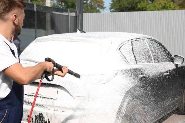 Mladý pracovník čištění automobil s vysokým tlakem vody jet v mytí aut — Stock fotografie