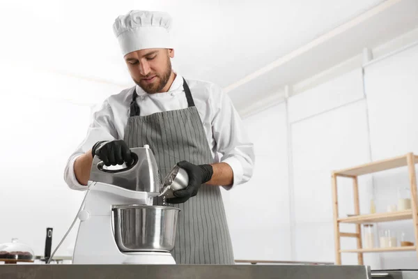 Chef de pastelaria masculino preparando massa em misturador na mesa da cozinha — Fotografia de Stock