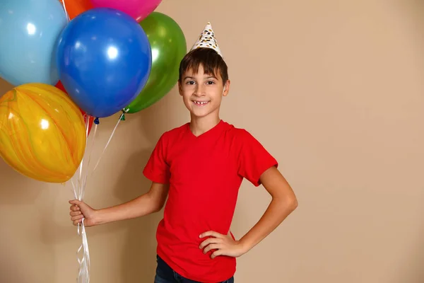 Szczęśliwy chłopiec z balonami na brązowym tle. Święto urodzin — Zdjęcie stockowe