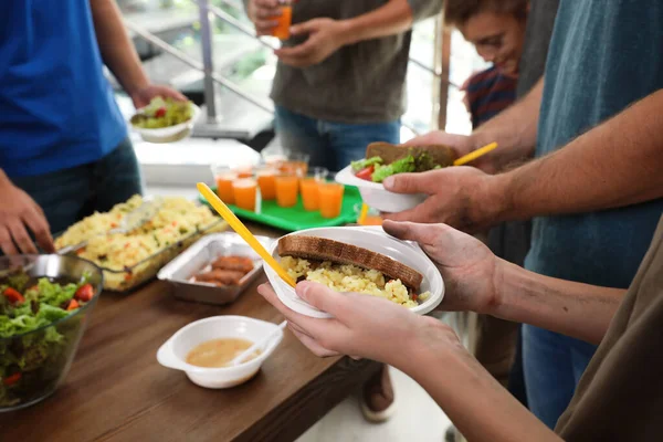 Pobres recibiendo comida de voluntarios en el centro de caridad, primer plano — Foto de Stock