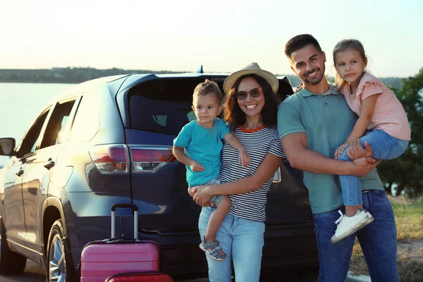 Famille heureuse avec valises près de la voiture au bord de la rivière — Photo