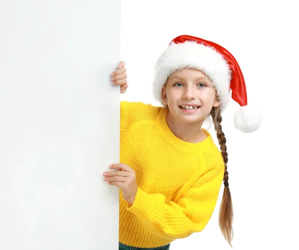 Criança feliz em chapéu de Papai Noel espreitando fora do banner em branco no fundo branco. Celebração de Natal — Fotografia de Stock