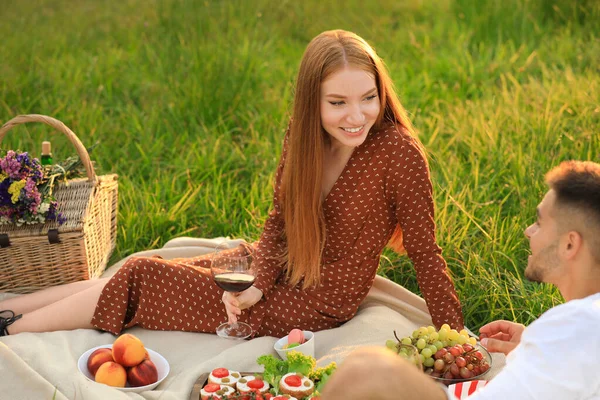 Şarabı olan mutlu genç çift yeşil parkta piknik yapıyor. — Stok fotoğraf