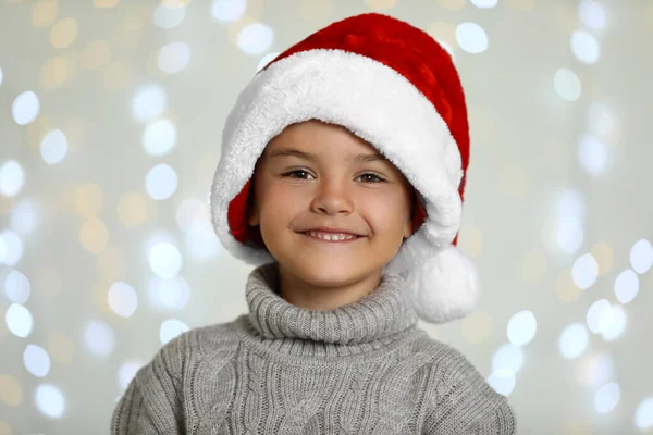 Щаслива маленька дитина в Санта-Капелюсі проти розмитих святкових вогнів. Свято Різдва — стокове фото