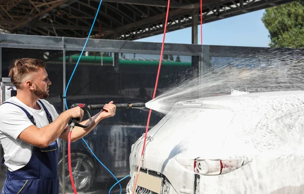 Mladý pracovník čištění automobil s vysokým tlakem vody jet v mytí aut — Stock fotografie