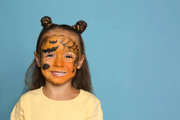 Schattig klein meisje met gezichtsbeschildering op blauwe achtergrond. Ruimte voor tekst — Stockfoto
