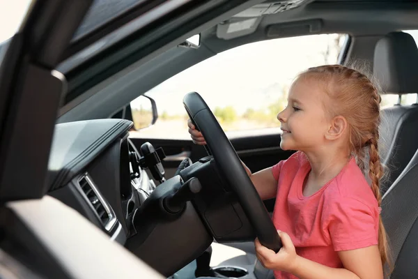 Kleines Mädchen spielt mit dem Lenkrad im Auto. Familienausflug — Stockfoto