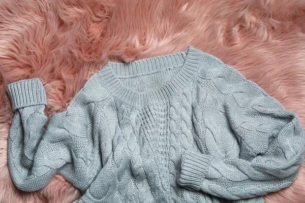 Grey knitted sweater on pink fur rug, flat lay — Stock Photo, Image