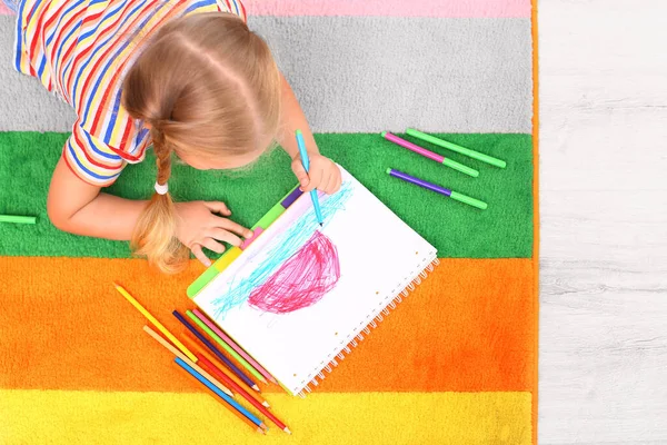 Little left-handed girl drawing on floor in room, above view — Stock Photo, Image