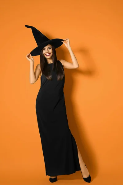 Hermosa mujer con traje de bruja para la fiesta de Halloween sobre fondo amarillo —  Fotos de Stock