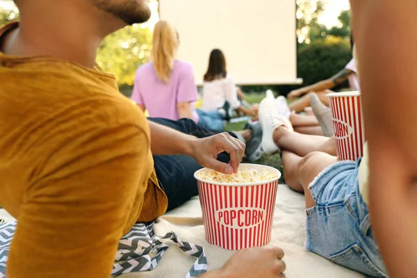 Młodzi ludzie z popcornem oglądają film w kinie na świeżym powietrzu, zbliżenie — Zdjęcie stockowe