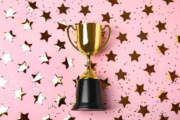 Gold trophy cup and confetti on light pink background, flat lay — Stock Photo, Image