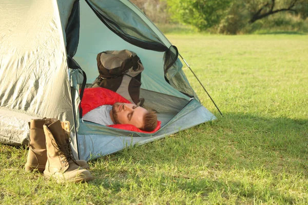 Giovane uomo a riposo nel sacco a pelo all'interno tenda da campeggio — Foto Stock