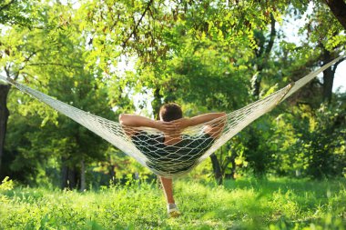 Yeşil bahçede rahat hamakta dinlenen genç adam