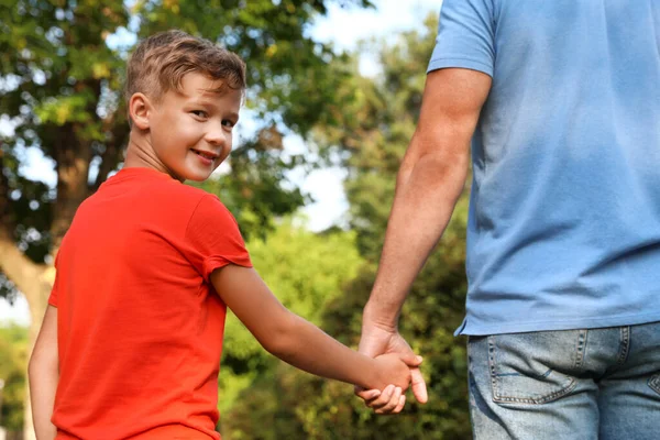 Мальчик и его отец держатся за руки на улице. Семейные выходные Стоковое Фото