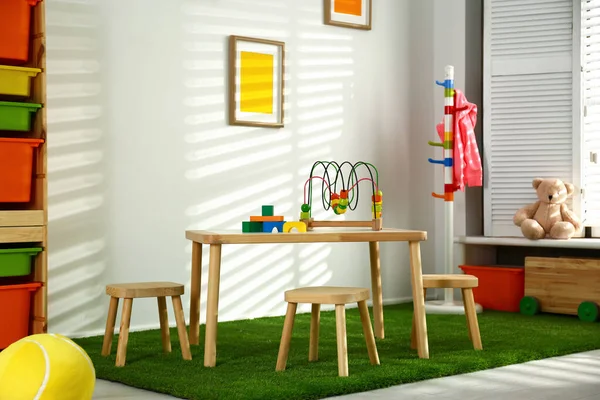 Стильный интерьер игровой комнаты с деревянным столом и стульями — стоковое фото