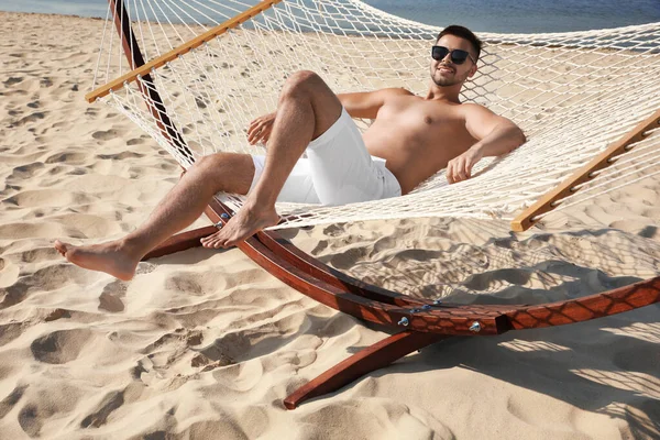 Hombre joven relajándose en hamaca en la playa — Foto de Stock