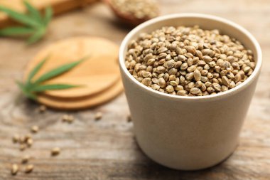 Tahta masadaki kasedeki organik kenevir tohumları.