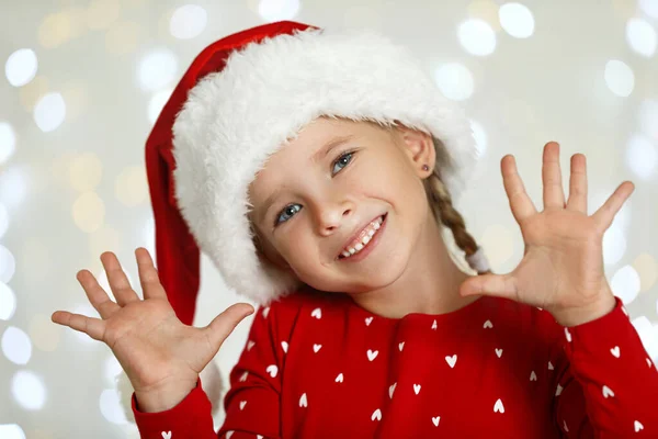 Criança feliz no chapéu de Papai Noel contra luzes festivas borradas. Celebração de Natal — Fotografia de Stock