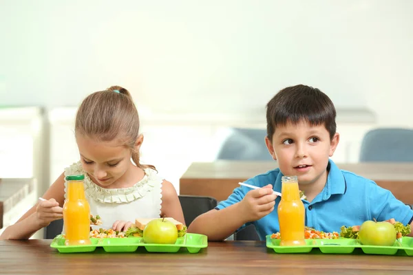 学校の食堂で昼食のために健康的な食べ物を食べる幸せな子供たち — ストック写真