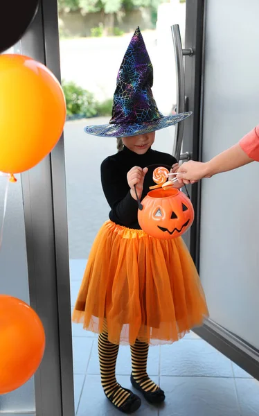 Linda niña vestida como bruja truco o trato en la puerta. Tradición Halloween —  Fotos de Stock