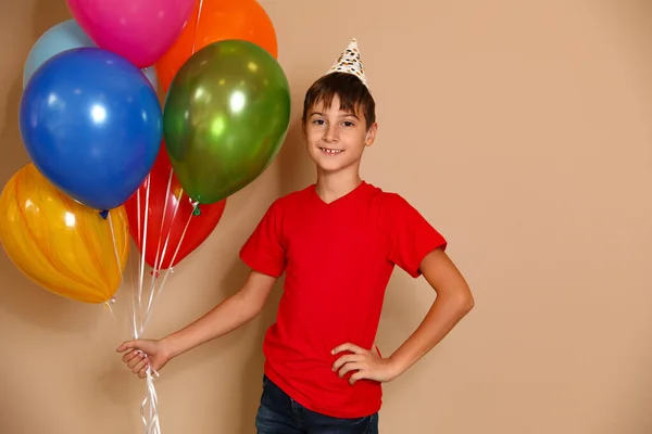 Kahverengi arka planda balonları olan mutlu çocuk. Doğum günü kutlaması — Stok fotoğraf