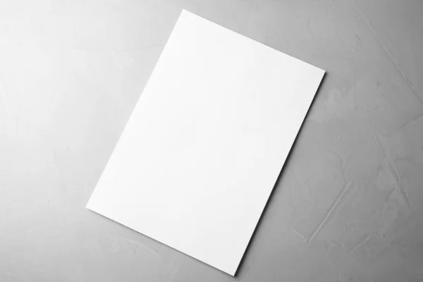 Prázdný papírový list na světle šedém kamenném pozadí, horní pohled. Vysmívat se designu — Stock fotografie